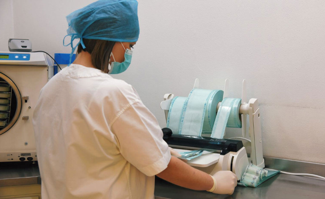 assistente del dentista con la mascherina che disinfetta gli strumenti