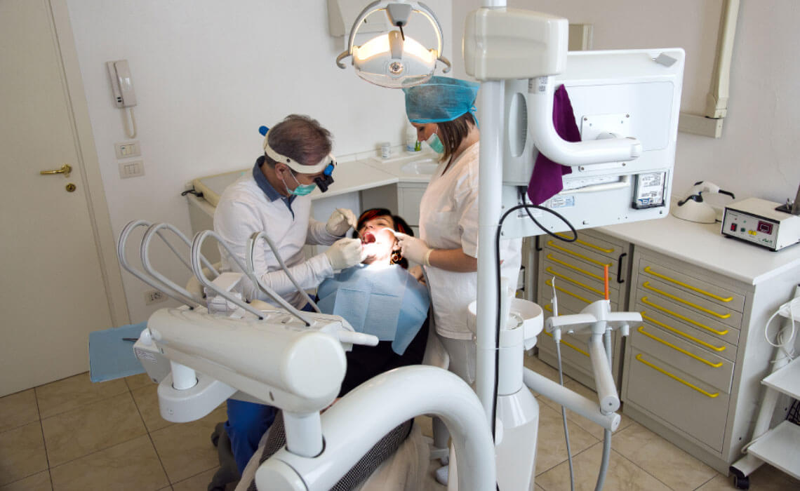 il dentista insieme all'assistente esegue un'otturazione alla paziente