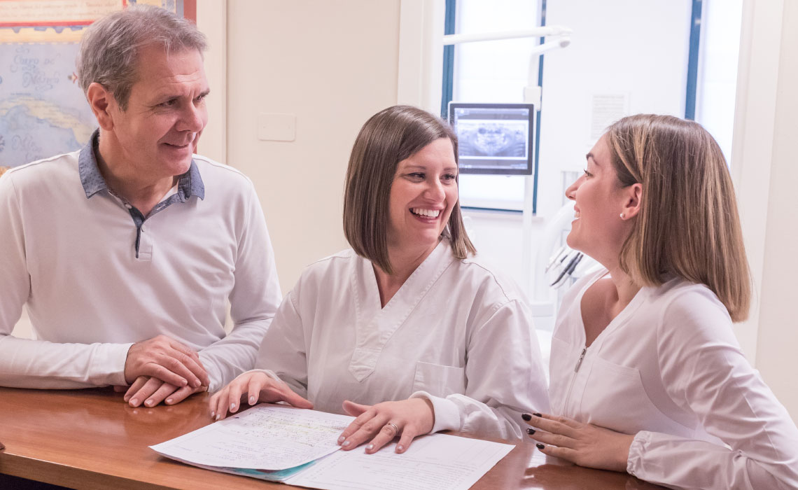 il dentista e le sue assistenti si consultano sulla cartella di un cliente